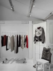 White-walled clothing shop with minimalist fashion display.