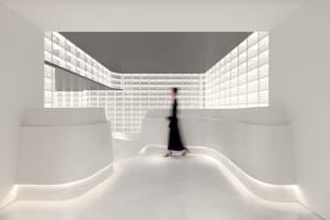 A minimalist interior design with a glass wall and curved white walls.