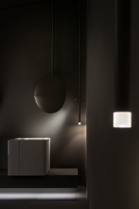 Modern minimalist bathroom with white ceramic sink, round mirror, and wall-mounted light fixture.