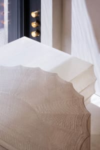 A modern bedroom with a textured, neutral-colored bedspread on a white platform bed.