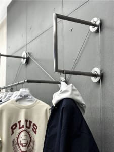 A modern clothing rack with metal rods and a string system for hanging clothes.
