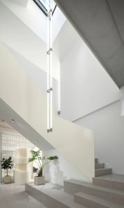 Modern, minimalist staircase with concrete steps and integrated lighting in a clean, white interior space.