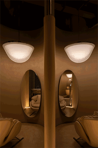 A modern living room with a glass pendant lamp hanging from the ceiling, reflecting light onto the surrounding space.