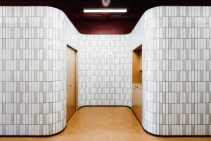 A modern bathroom with white tiled walls and beige flooring.