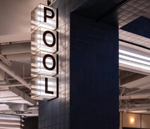 A minimalist hotel lobby with tiled walls and glass features.