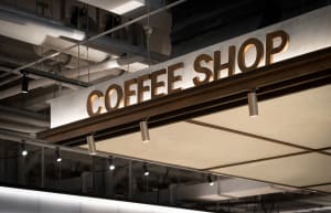 Modern, industrial-style coffee shop signage with metallic cladding.
