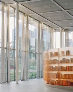 A modern library interior with glass walls and bookshelves.