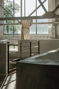 A minimalist interior space featuring exposed concrete and steel elements.
