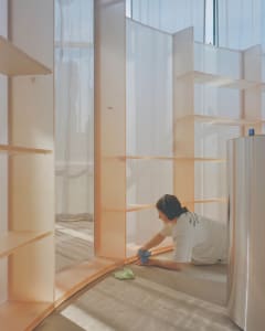 Person cleaning a minimalist interior with white acrylic and copper materials
