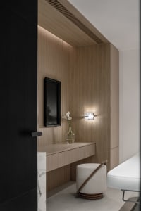 A minimalist interior design featuring a wooden frame with a vase of flowers and a white ottoman.