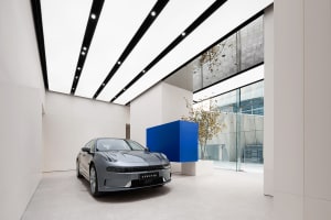 High-angle view of a sleek, modern showroom with a luxury car on display, illuminated by linear lighting and surrounded by mi