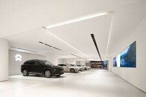 A modern car showroom with a minimalist, industrial design featuring concrete floors and LED lighting.