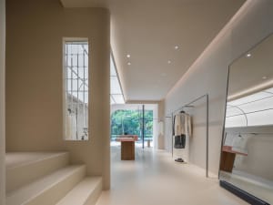 Modern clothing store interior with minimalist design featuring neutral colors and wooden accents.