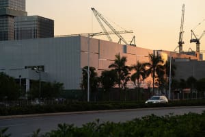 Modern building with metal cladding at a construction site surrounded by palm trees.