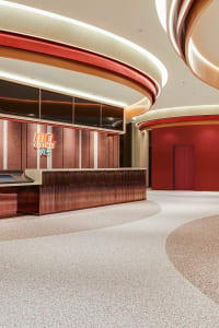 A modern cinema lobby featuring a metallic and terrazzo interior with red accent walls.