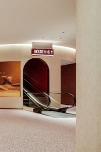 Modern shopping center with glass walls and concrete floors, illuminated by ceiling lights.