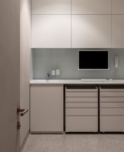 A minimalist office space with a white desk, drawers, and cabinets.