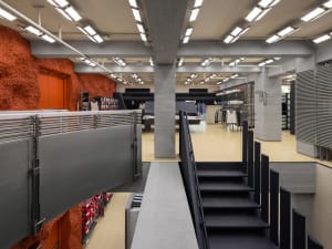 Interior of an industrial-style shopping centre with exposed concrete walls and ceiling beams.