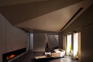 A modern residential interior with concrete walls, a circular sofa, and a fireplace.