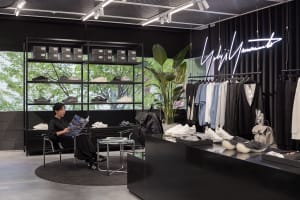 A modern retail store with black materials and a black sign displaying 'Yohji Yamamoto'.