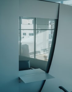 A minimalist chatroom interior with a modern window design, white walls, and metallic accents.