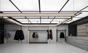 A minimalist retail shop with concrete walls, black metal hangars, and hanging clothing.