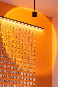 An orange wall adorned with numerous mahjong tiles arranged in a grid pattern.