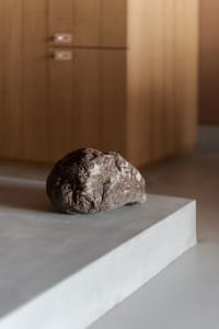 A minimalist interior design featuring a concrete stone object on a platform.
