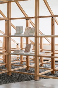 A minimalist wooden library with open shelving and books.