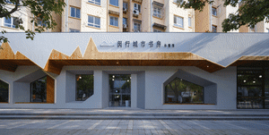 Modern bookstore exterior with wooden accents and concrete walls, featuring large windows and a glass canopy.