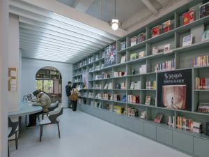 A modern library interior with concrete walls and metal shelves.