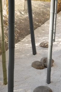 A minimalist bamboo walkway lined with white pebbles, creating a serene and tranquil outdoor space.