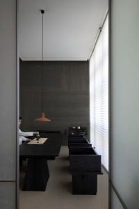 Minimalist-designed living room featuring a dark wooden tea table and glass tea set, with a tea ceremony in progress.