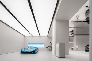 A modern automotive showroom with minimalist design, featuring concrete and glass materials.
