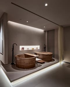 A modern minimalist bathroom featuring concrete and wooden bathtubs.