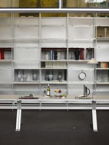 A metal and glass display case holding various objects within an interior design setting.