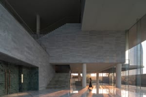 Modern corporate hallway with concrete walls and floors, featuring a sleek, minimalist design.