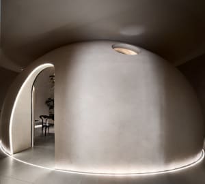 A modern living room with a concrete wall and floor, featuring minimalistic design elements.