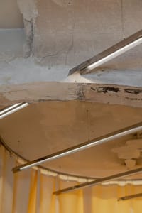 Exposed concrete ceiling with metal pipes and conduits.