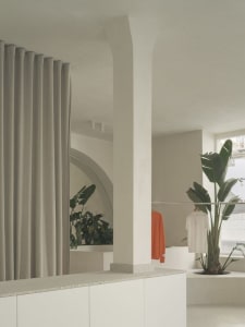 A minimalist clothing shop with concrete walls and large windows displaying fashion items.