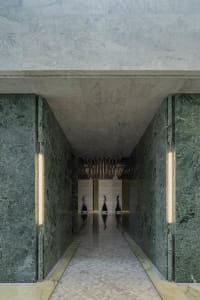 A contemporary corridor with green marble walls and a reflective floor.