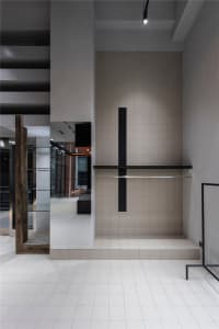 A minimalist modern industrial interior space featuring concrete walls and floors with dark metal accents.