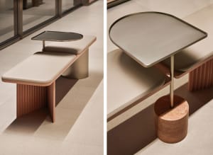 A modern bench featuring a cushioned seat, a small table attached to the top, and a sleek design with a combination of leathe