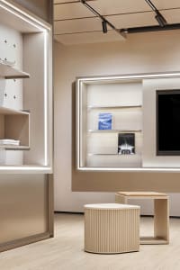 Modern retail shop with light wood interiors and illuminated shelves.