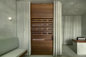 Modern minimalist storefront with concrete walls, wood cabinetry, concrete floors, and a white curtain.