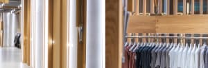 Modern retail store with wooden walls and a hanging rail displaying casual clothing.