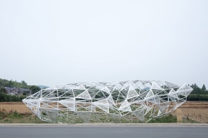 A modern, white metal frame structure in an open field.