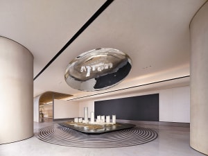 A modern marble lobby with a large metallic ceiling sculpture and architectural model on the floor.