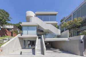 Modern building facade featuring a unique concrete structure and a glass canopy.