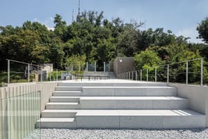 A modern park featuring concrete stairs surrounded by greenery and trees.